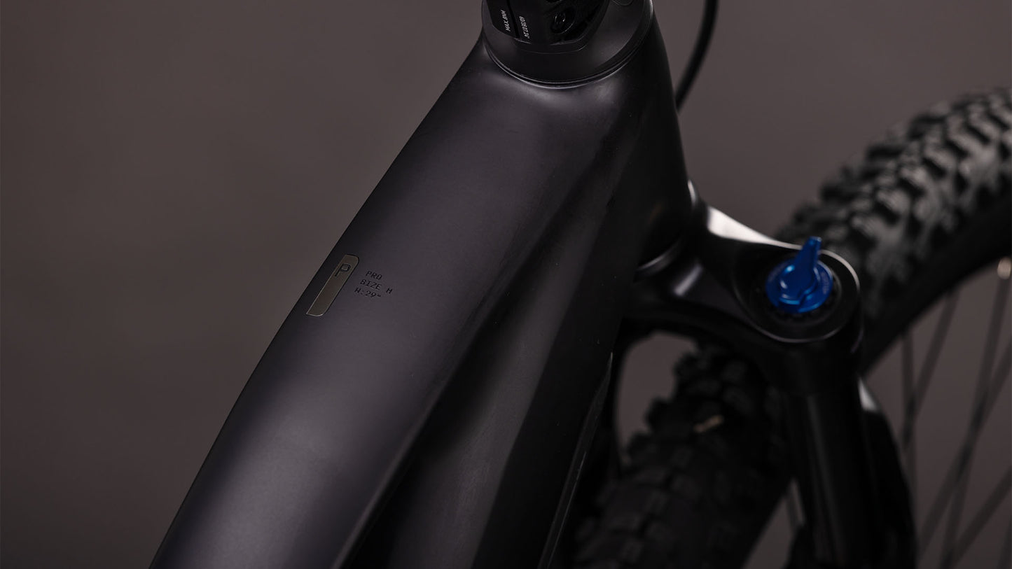 Nahaufnahme des mattschwarzen CUBE Reaction Hybrid Pro 800 blackline Trapeze 2026 Rahmens mit Oberrohr, Federgabel mit blauem Knauf und integriertem Display. Ausgestattet mit Bosch CX Antrieb und 800 Wh Akku; neutraler unscharfer Hintergrund.