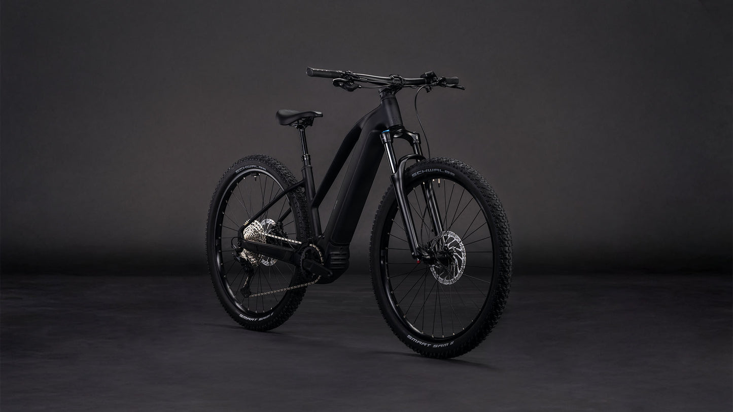 Das CUBE Reaction Hybrid Pro 800 blackline Trapeze 2026 E-Mountainbike präsentiert sich vor dunklem Hintergrund mit dicken Reifen, einem stabilen Rahmen, einer fortschrittlichen Schaltung und einem leistungsstarken Bosch CX-Antrieb mit 800-Wh-Akku für lange Fahrten.