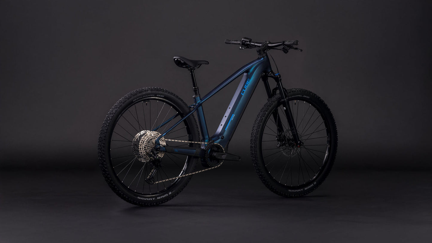 Das CUBE Reaction Hybrid Pro 800 nebular'n'dazzle 2026, ein dunkelblaues E-Mountainbike mit dicken Reifen, stabilem Rahmen, fortschrittlicher Schaltung und leistungsstarkem Bosch CX-Antrieb, steht vor einem schlichten dunklen Hintergrund.