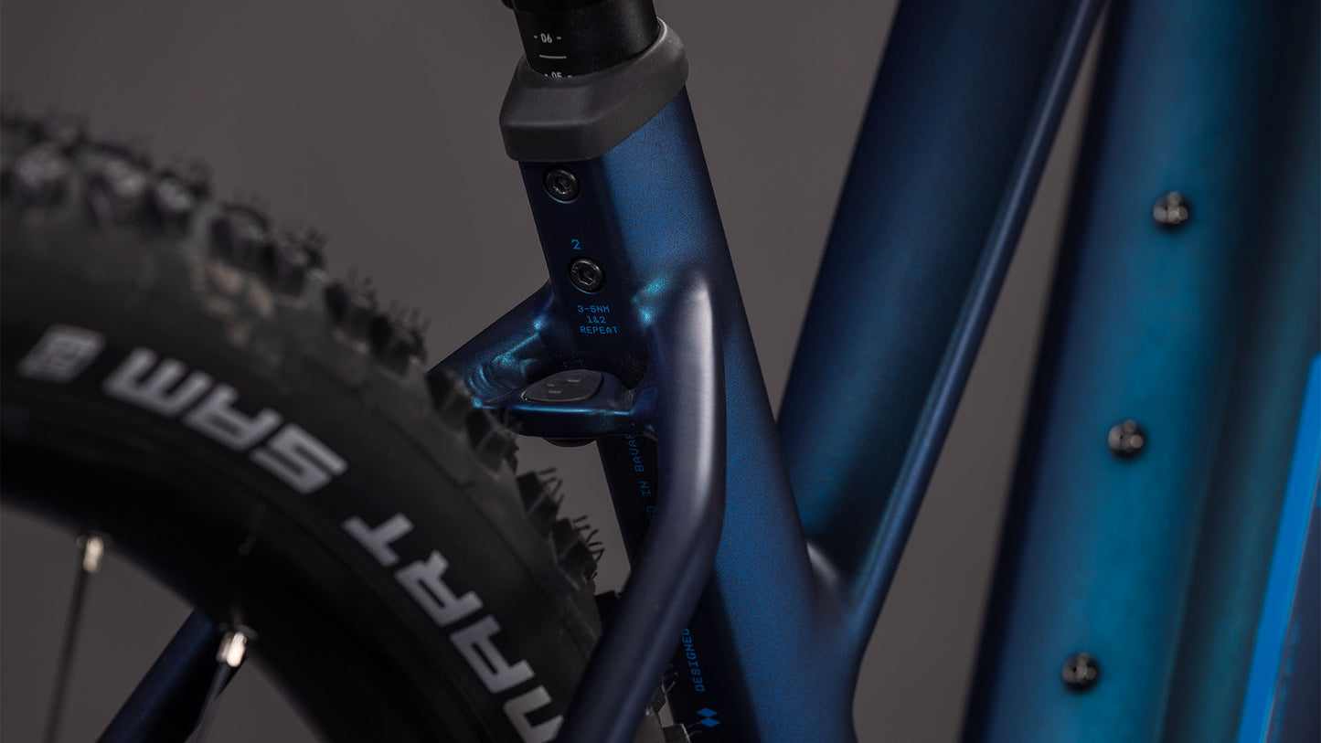 Die Nahaufnahme des CUBE Reaction Hybrid Pro 800 nebular'n'dazzle Trapeze 2026 zeigt den blauen Rahmen, das Sitzrohr, die markierte Sattelstützenklemme und den Hinterreifen mit SRAM-Branding. Ausgestattet mit Bosch CX Antrieb und einem 800 Wh Akku für Top-Trail-Performance.