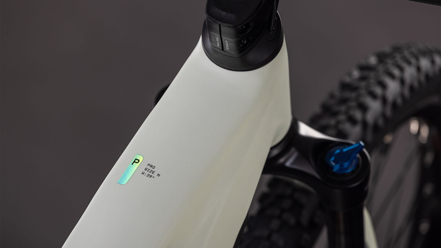 Nahaufnahme des CUBE Reaction Hybrid Pro 800 desertstone'n'driedherbs 2026 Rahmens mit einem kleinen beleuchteten Digitaldisplay, einem Teil des Lenkers, der Federgabel mit Bosch CX-Antrieb und einem Noppenreifen im Hintergrund.