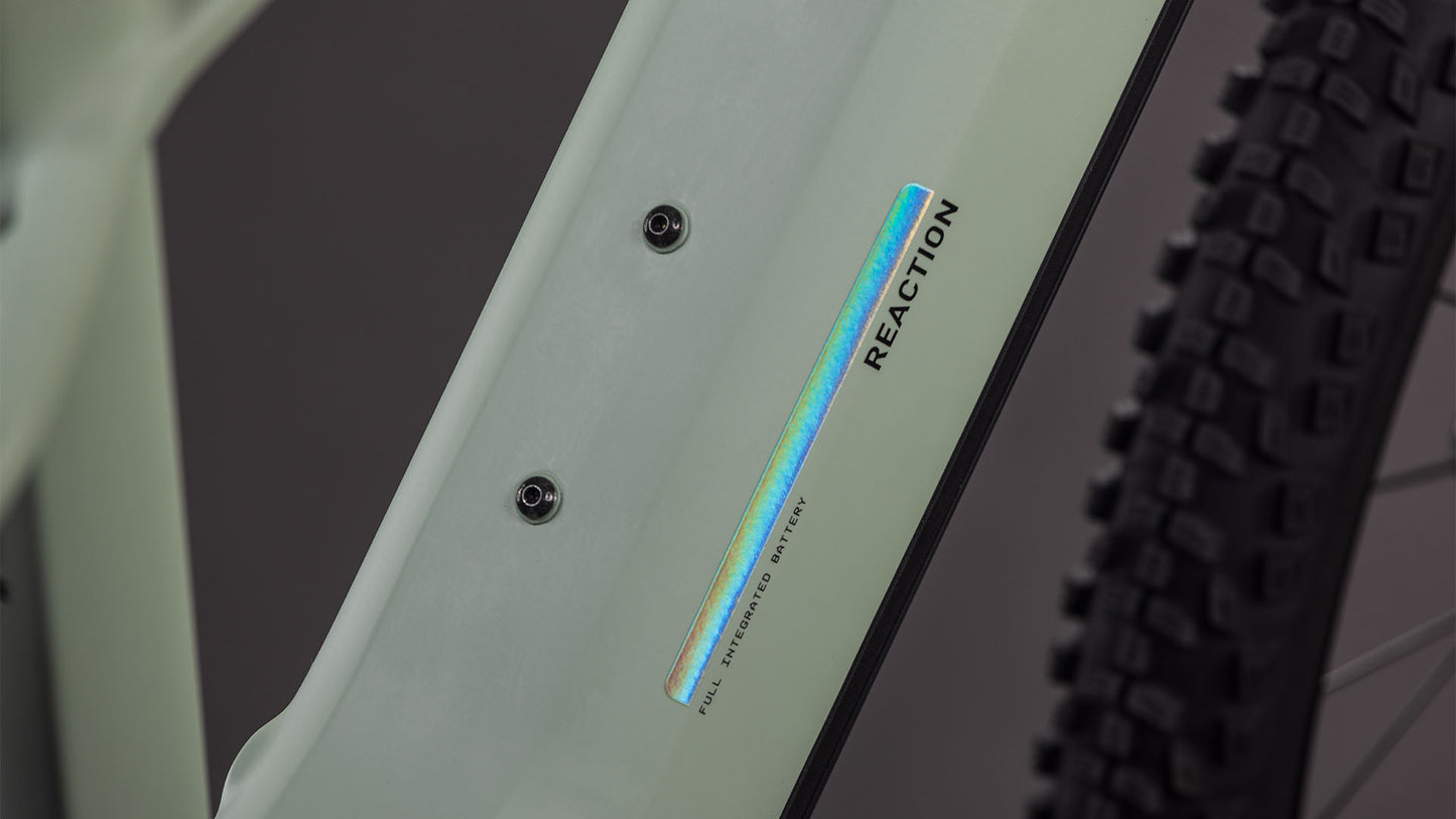 Nahaufnahme des CUBE Reaction Hybrid Pro 800 desertstone'n'driedherbs 2026-Rahmens mit "REACTION"- und irisierendem "FULL INTEGRATED BATTERY"-Schriftzug, zwei Schraubenbefestigungen, einem Teil eines groben Reifens und Bosch CX-Antriebsdetails.