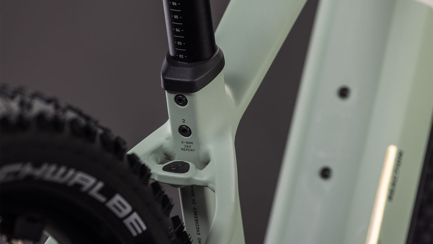 Nahaufnahme eines CUBE Reaction Hybrid Pro 800 desertstone'n'driedherbs 2026 Rahmens, wobei die Sattelstütze, das Sitzrohr mit den Einstellmarkierungen und ein Teil eines schwarzen Schwalbe-Reifens hervorgehoben werden. Der sanft verschwommene Hintergrund hebt die Details hervor.