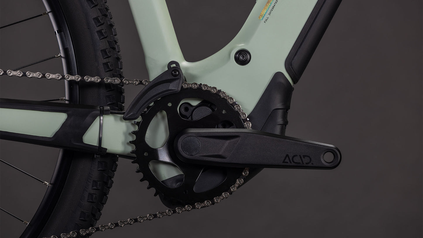 Nahaufnahme der CUBE Reaction Hybrid Pro 800 Kurbelgarnitur und des Kettenblatts, mit einem Teil des Hinterradreifens und der Kette auf einem hellgrünen und schwarzen Rahmen, mit Bosch CX-Antriebsdetails und ACID-Branding auf dem Kurbelarm.
