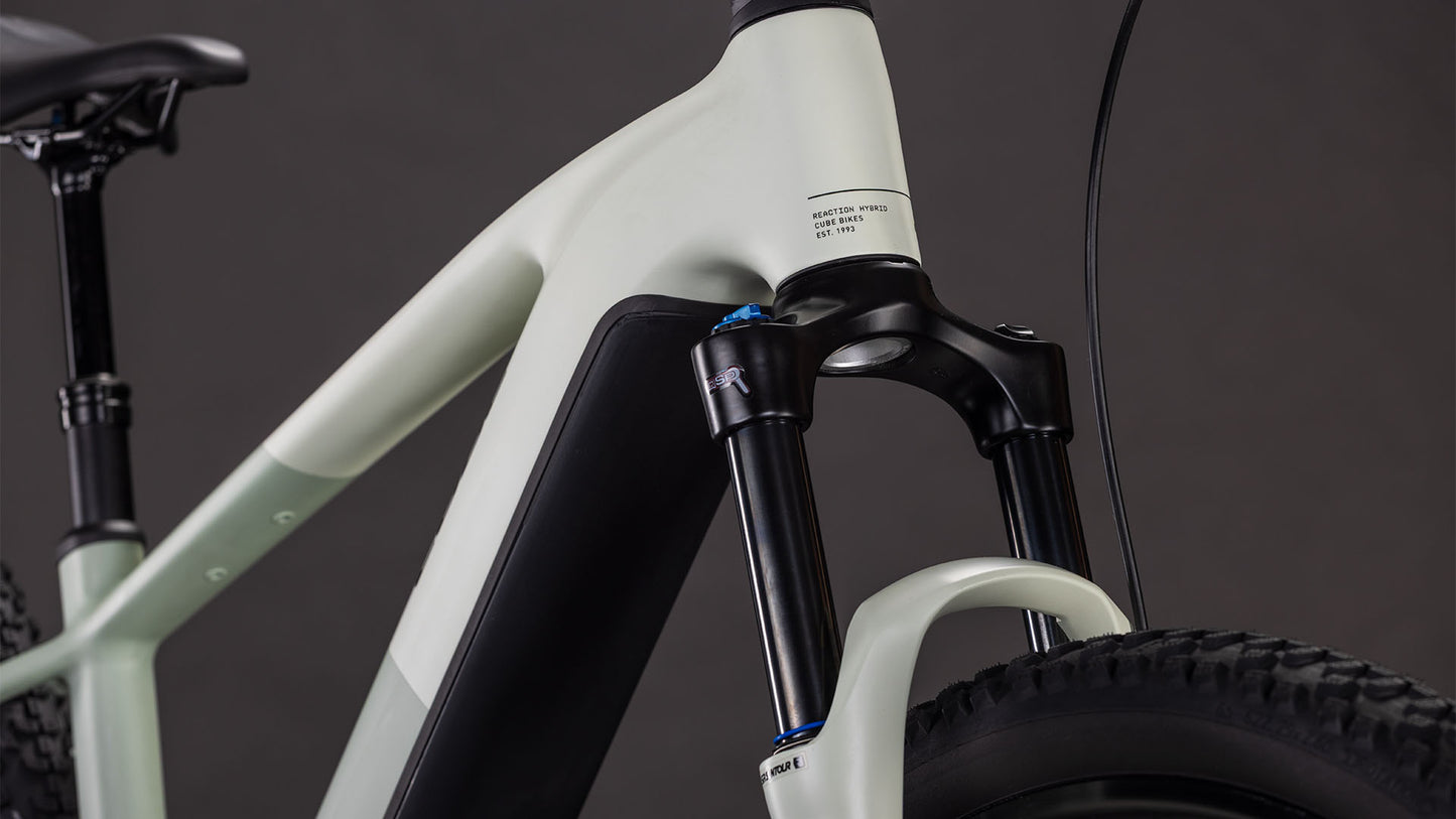 Seitliche Nahaufnahme des CUBE Reaction Hybrid Pro 800 desertstone'n'driedherbs 2026 E-Mountainbike-Rahmens mit Bosch CX-Antrieb, 800-Wh-Akku, Federgabel, Vorderradprofil und Sitzrohr vor dunklem Hintergrund.