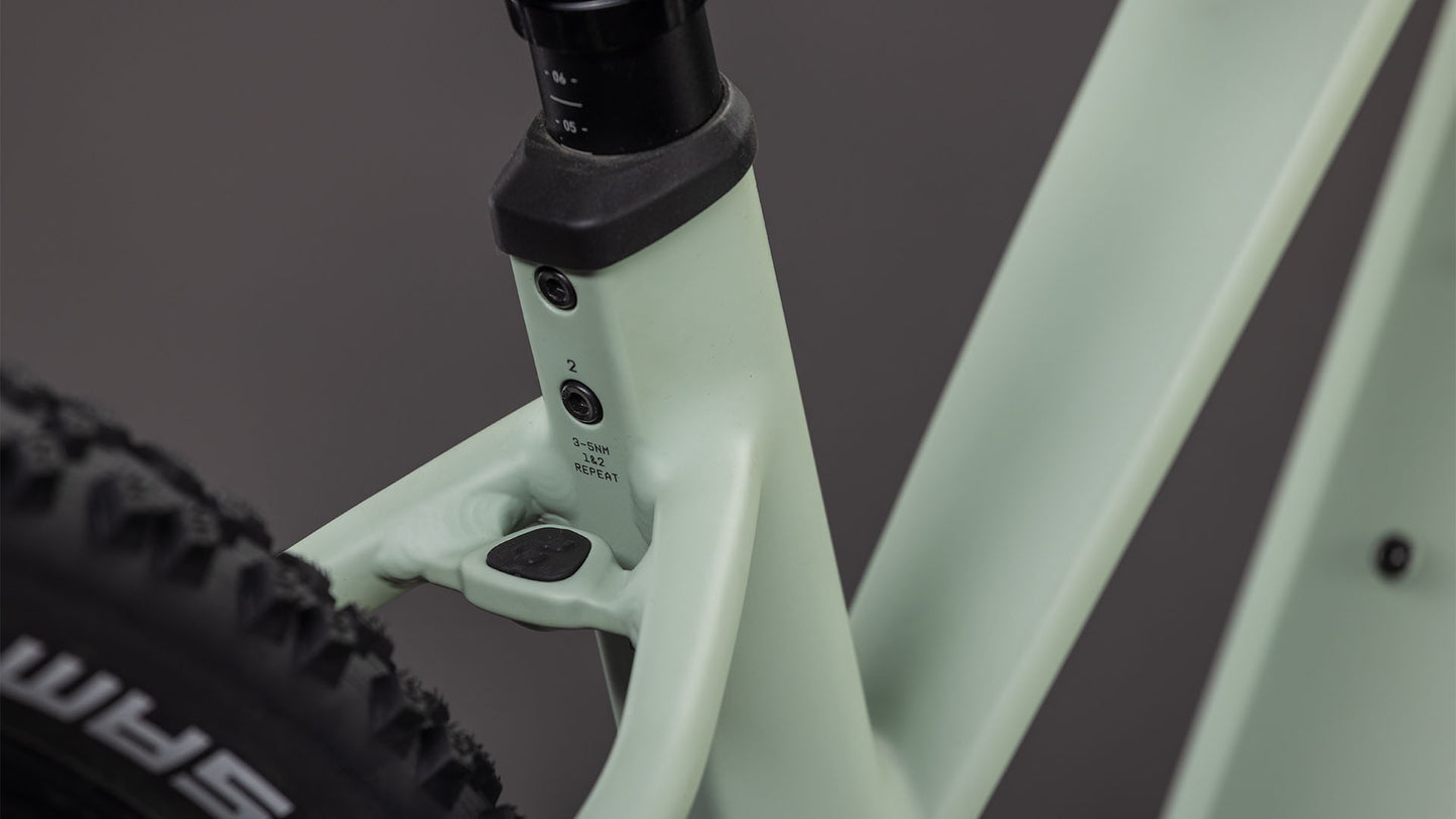 Die Nahaufnahme des Cube Reaction Hybrid Pro 800 desertstone'n'driedherbs Trapeze 2026 von CUBE zeigt das Sitzrohr, die Sattelstütze, den Hinterreifen, die Einstellschrauben und eine Gummiabdeckung am Rahmen - ideal für den leistungsstarken 800 Wh Akku.