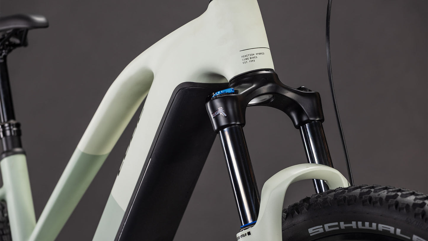 Nahaufnahme des Vorderrahmens, der Federgabel und des Reifens des CUBE Reaction Hybrid Pro 800 Trapeze 2026 vor einem dunklen Hintergrund. Seine robuste, matte Konstruktion sticht hervor. Der Bosch CX Antrieb sorgt für kraftvolle E-Mountainbike-Fahrten.