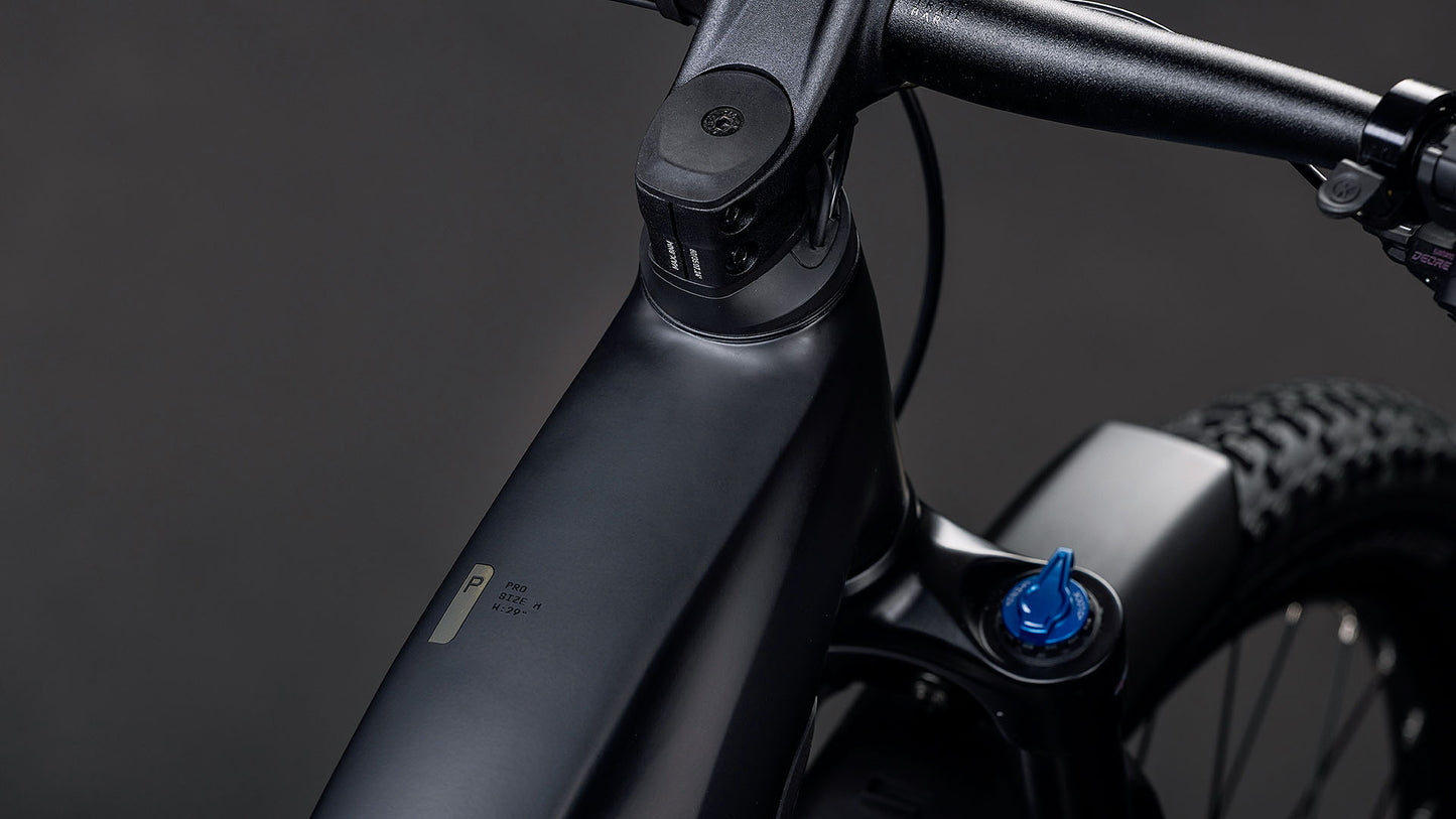 Nahaufnahme des mattschwarzen CUBE Reaction Hybrid Pro 800 FE blackline 2026 E-Bike-Rahmens und -Lenkers mit blauer Federgabelverstellung, angetrieben durch den Bosch CX-Motor für verbesserte Leistung, vor dunklem Hintergrund.