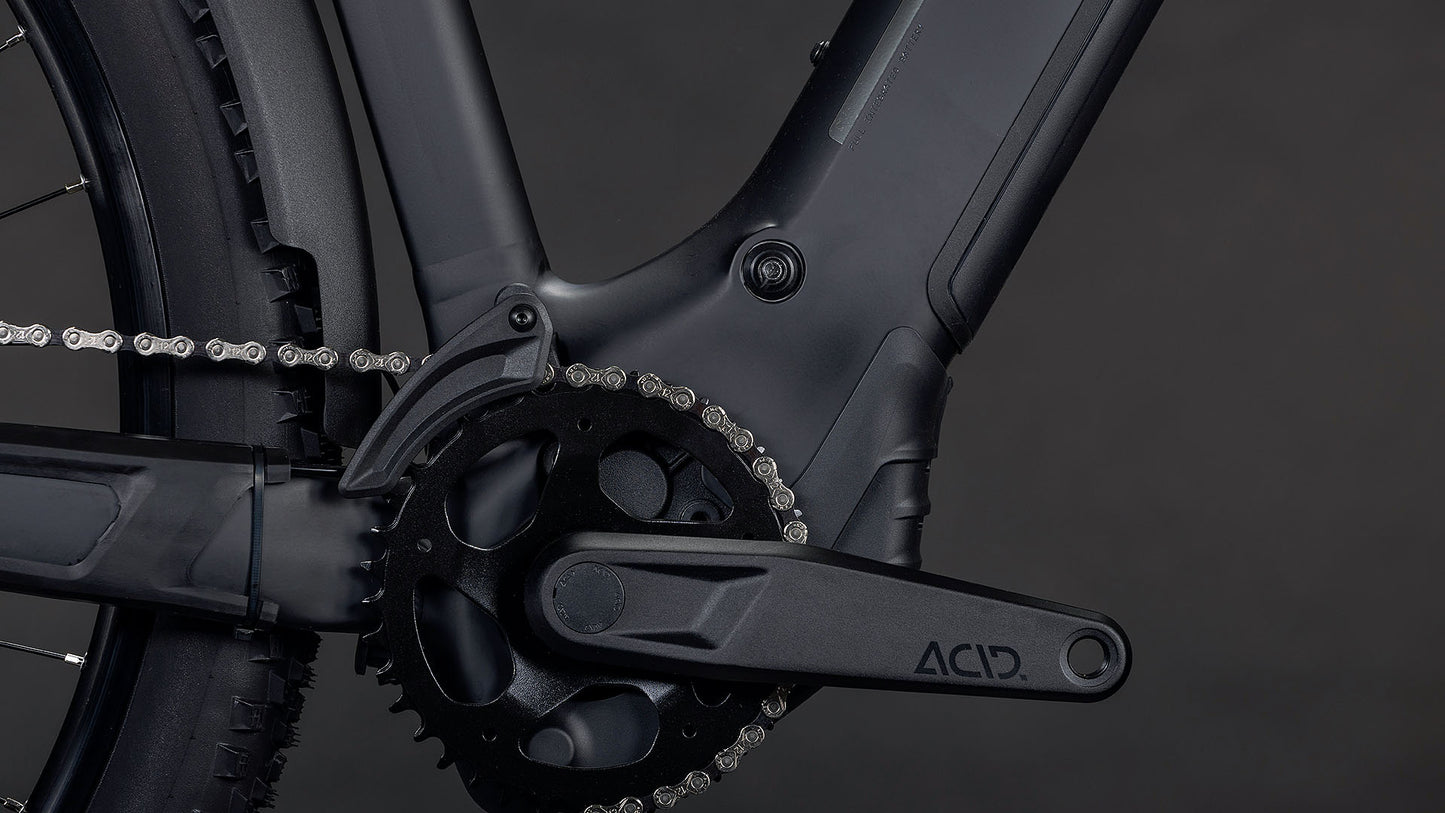 Nahaufnahme einer CUBE Reaction Hybrid Pro 800 FE blackline 2026 E-Bike Kurbelgarnitur und Kettenblatt, mit ACID-gekennzeichnetem Kurbelarm, Rahmen, Kette und Hinterradreifen sichtbar. Mit Bosch CX-Motor für starke Leistung vor dunklem Hintergrund.