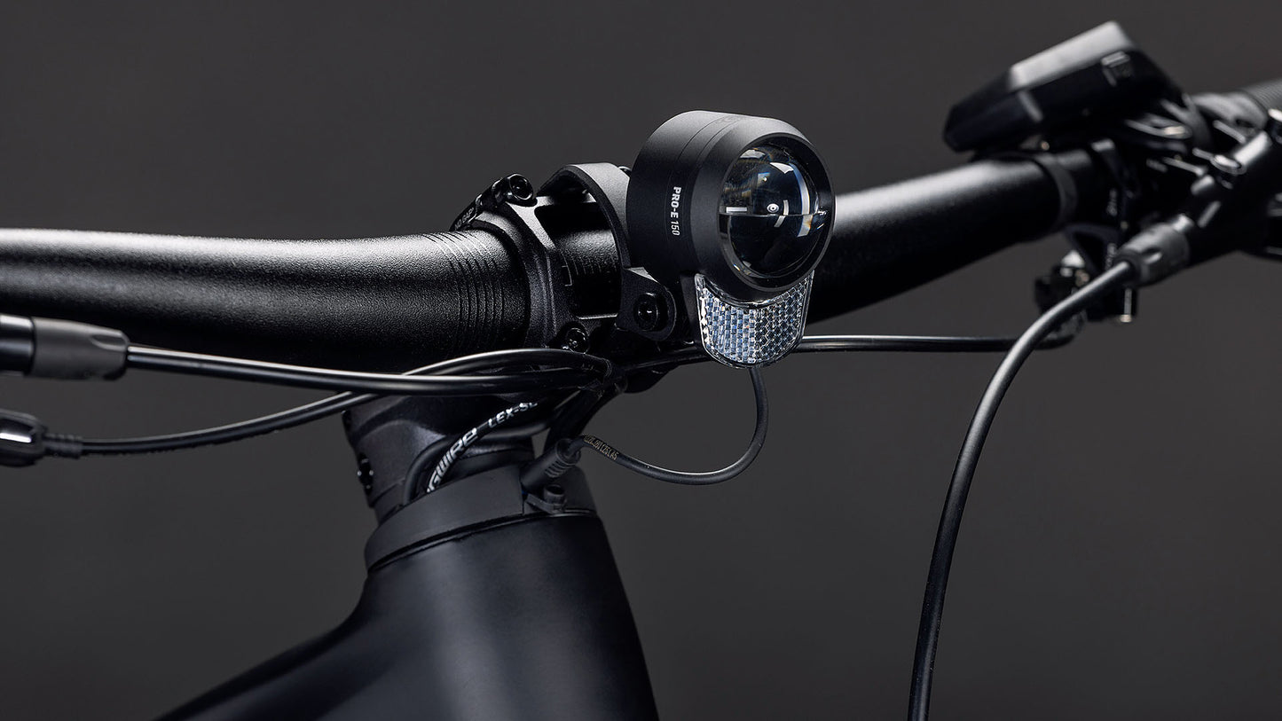 Nahaufnahme des CUBE Reaction Hybrid Pro 800 FE blackline 2026 Lenkers mit Kabeln, montiertem Frontlicht und reflektierendem Panel vor einem dunklen Hintergrund - mit fortschrittlicher Technik wie dem Bosch CX Motor und der Shimano XT Schaltung.