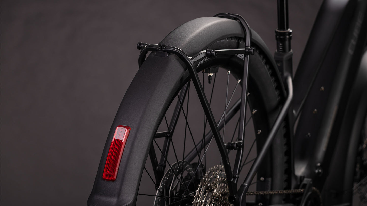Nahaufnahme des Hinterrads eines CUBE Cube Reaction Hybrid Pro 800 FE blackline Trapeze 2026, mit Schutzblech mit rotem Reflektor, Rahmen, Shimano XT 12-fach Schaltung, Kette und Stützstreben vor dunklem Hintergrund.