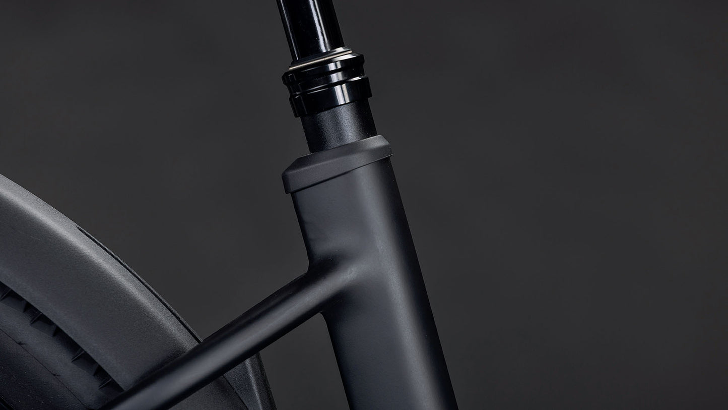 Nahaufnahme des CUBE Reaction Hybrid Pro 800 FE blackline Easy Entry 2026, die den mattschwarzen Rahmen, den Bosch CX Motor und die nahtlose Integration von Oberrohr, Sitzrohr und Hinterrad vor einem dunklen Hintergrund zeigt.