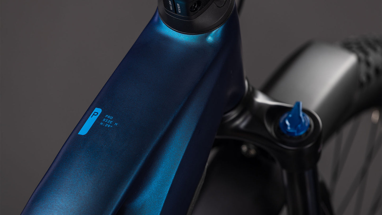 Nahaufnahme des CUBE Cube Reaction Hybrid Pro 800 FE nebular'n'dazzle 2026 E-Bike-Rahmens mit digitalem Display, das den Leistungsmodus anzeigt und den Lenker, die Federgabel, den Bosch CX Motor und einen Teil des Vorderrads vor einem dunklen Hintergrund hervorhebt.