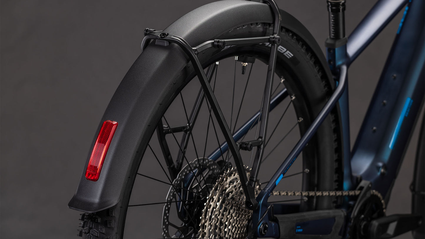 Nahaufnahme des Hinterrads eines CUBE Cube Reaction Hybrid Pro 800 FE nebular'n'dazzle 2026 E-Bike, mit schwarzem Schutzblech, rotem Reflektor, Shimano XT Schaltung und einem Teil des Rahmens vor einem dunklen Hintergrund.