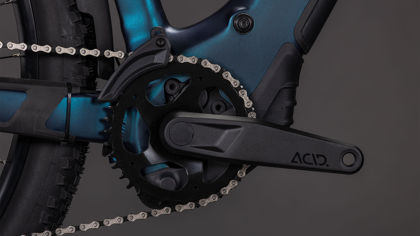 Nahaufnahme einer schwarzen Kurbelgarnitur, eines schwarzen Kettenblatts und einer schwarzen Kette am CUBE Reaction Hybrid Pro 800 FE nebular'n'dazzle 2026 E-Bike, mit dem ACID-Logo auf dem Kurbelarm und der Integration des Bosch CX-Motors vor einem dunkelgrauen Hintergrund.