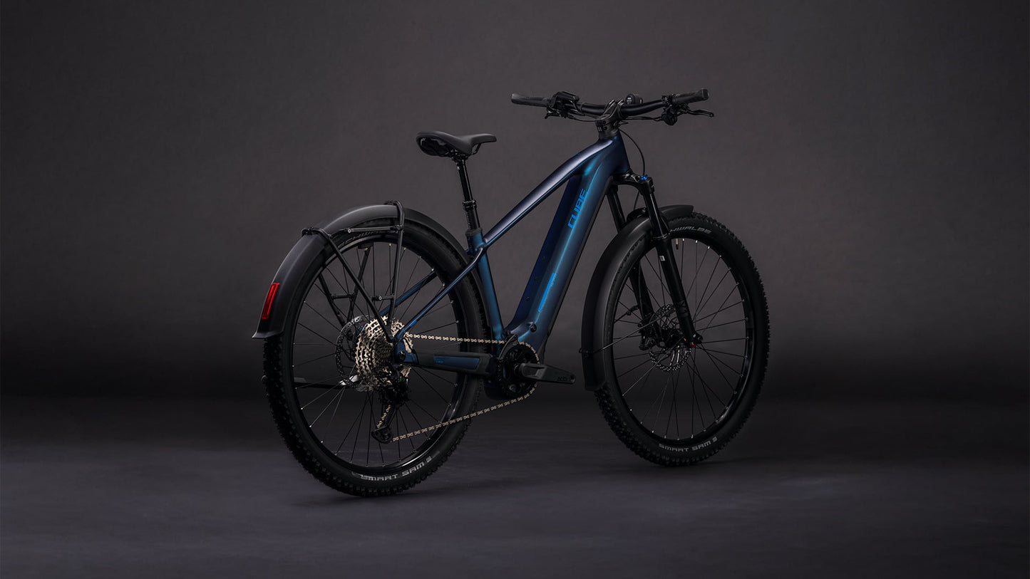 Das CUBE Reaction Hybrid Pro 800 FE nebular'n'dazzle 2026 ist ein elegantes E-Bike-Mountainbike mit dunkelblauem Rahmen, Bosch CX-Motor, breiten Reifen, Scheibenbremsen, Schutzblechen vorne und hinten und rotem Rückstrahler auf dunkelgrauem Hintergrund.