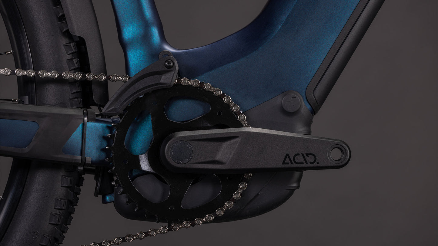 Nahaufnahme der Kurbelgarnitur und der Kette des Cube Reaction Hybrid Pro 800 FE Easy Entry 2026 E-Bike, mit detaillierten Zahnrädern, Kettenblatt und dem "ACID"-Logo auf dem Kurbelarm, auf einem blau-schwarzen CUBE-Rahmen vor dunklem Hintergrund.