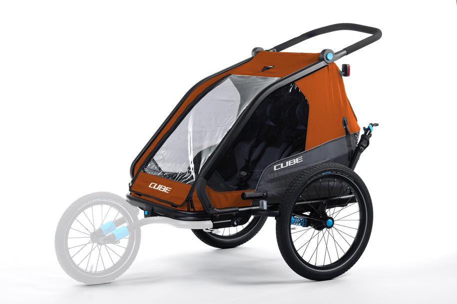 Der CUBE Kinder Fahrradanhänger Double CMPT X Actionteam von Cube ist in den Farben Orange und Grau gehalten und verfügt über große schwarze Räder, eine transparente Frontabdeckung, Insektenschutz und eine verblasste Abbildung eines optionalen Kinderwagen-Vorderradaufsatzes.