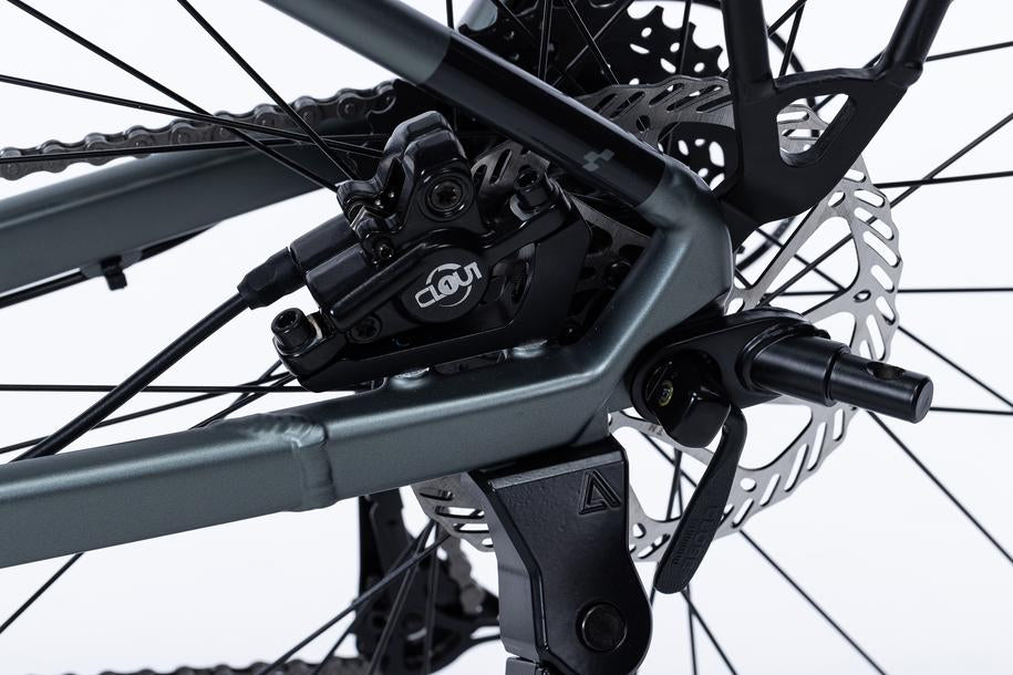 Nahaufnahme der Cube CUBE Kupplung Universal für Kinder Fahrradanhänger Double CMPT, die die hintere Scheibenbremsanlage in Goslar mit Bremssattel, Bremsscheibe, Rahmenteil und Speichen mit Blick auf die Detailmechanik zeigt.