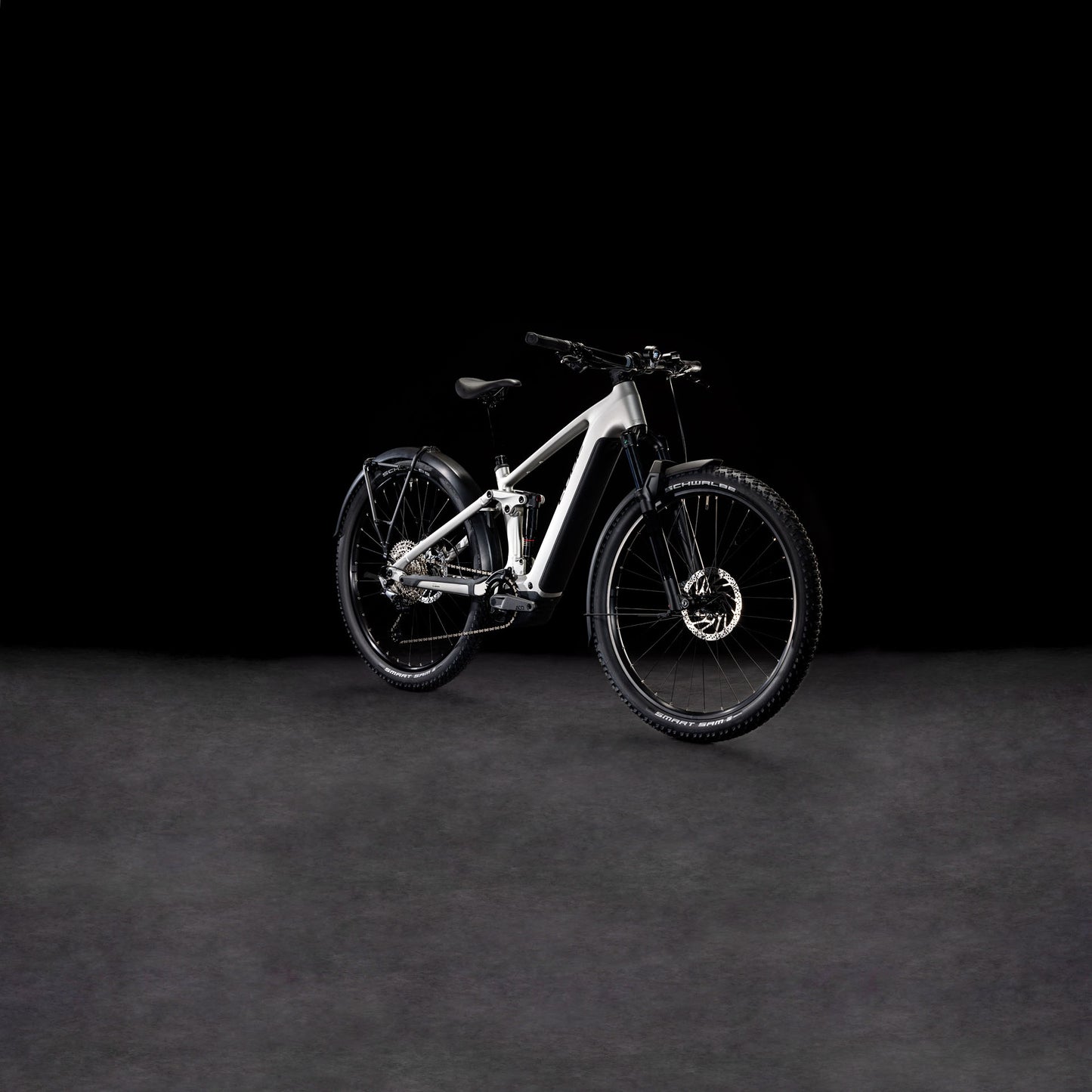 Das CUBE Stereo Hybrid ONE22 Race 800 Allroad silver'n'black 2025 Elektro-Mountainbike mit dicken Reifen, Scheibenbremsen und einem Bosch CX-Motor wird vor einem dunklen, minimalistischen Hintergrund präsentiert.