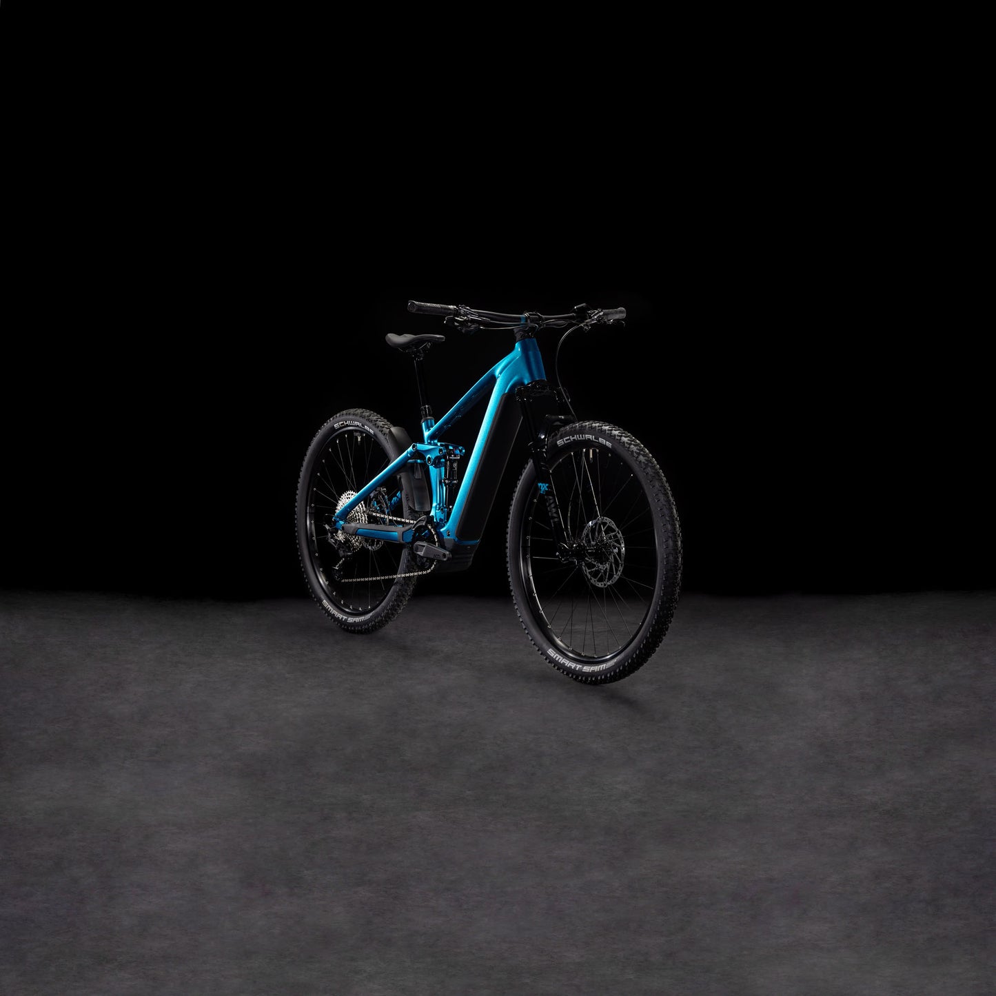 Das CUBE Stereo Hybrid ONE22 SLX 800 electricblue'n'black 2025 Mountainbike besticht durch eine dunkle, strukturierte Oberfläche mit schwarzem Hintergrund, die das moderne Design und die robusten Reifen hervorhebt.