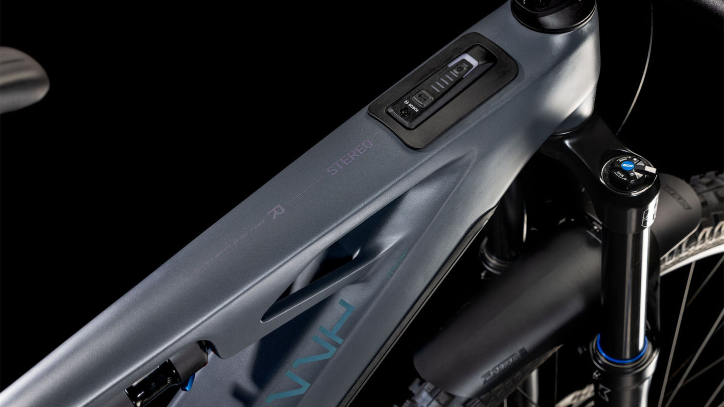 Nahaufnahme des CUBE Stereo Hybrid ONE77 HPC Race 800 slapgrey'n'prism 2025 Rahmens. Hervorzuheben sind das mattgraue Oberrohr mit integrierter Elektronik, die Federgabel und der Lenkervorbau vor einem schwarzen Hintergrund.