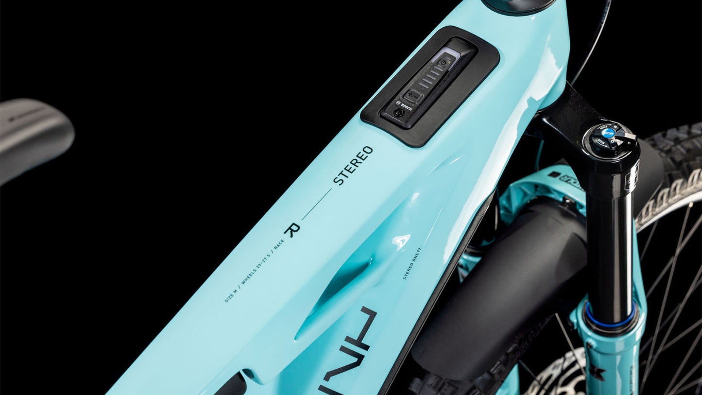 Nahaufnahme eines CUBE Stereo Hybrid ONE77 HPC Race 800 Dazzle´n´Black 2025-Rahmens, der das integrierte Bedienfeld, das STEREO-Branding, einen Teil der Vorderradfedergabel und Details des Bosch CX-Motors vor einem schwarzen Hintergrund zeigt.