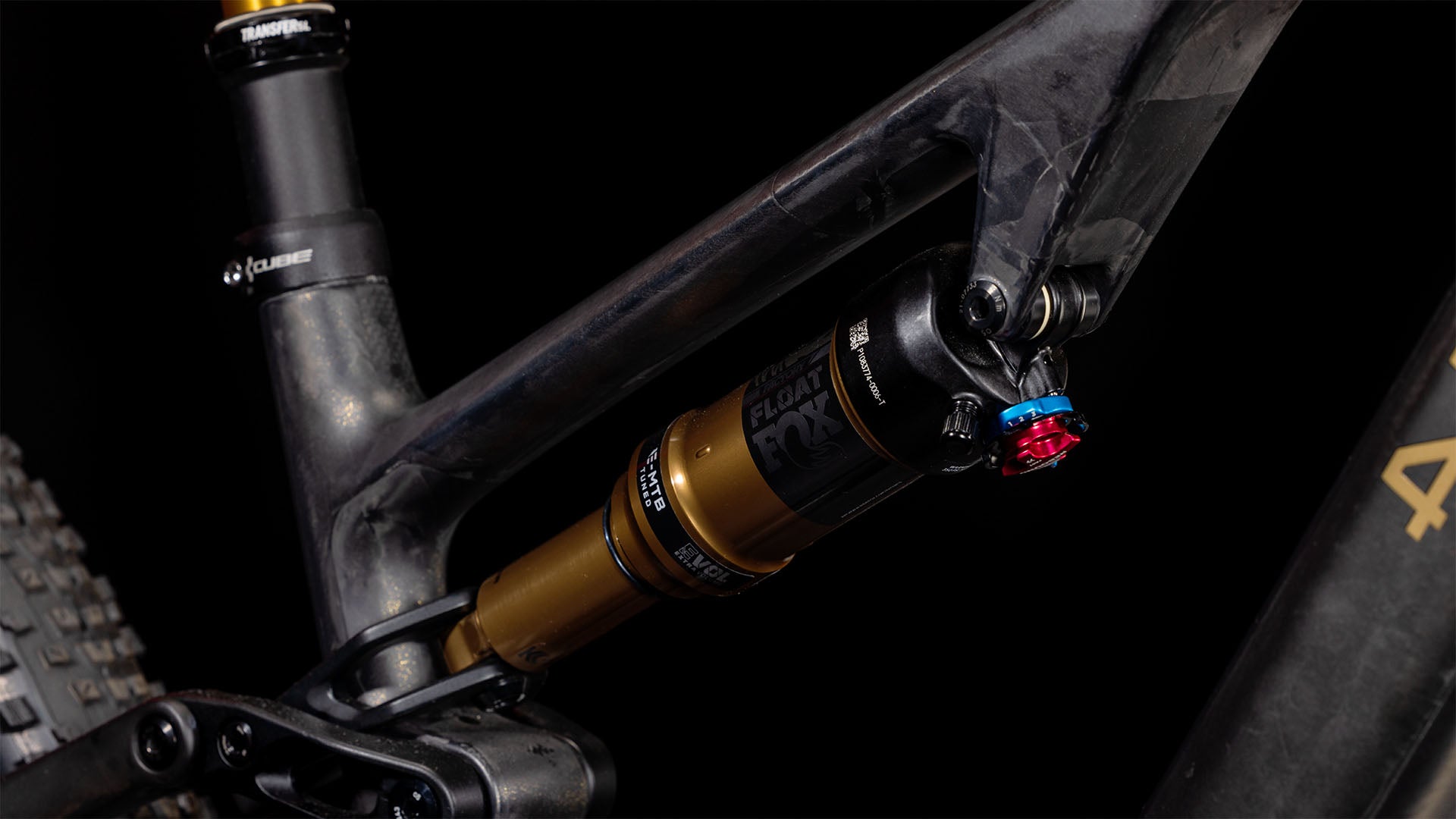 Nahaufnahme der Hinterradaufhängung des CUBE AMS Hybrid ONE44 C:68X SLT 400X 29 carbon'n'golddust 2025, die einen gold-schwarzen FOX Float-Dämpfer auf dem superleichten C:68X-Carbonrahmen mit sichtbaren Noppen und einem Teil des Hinterreifens zeigt.