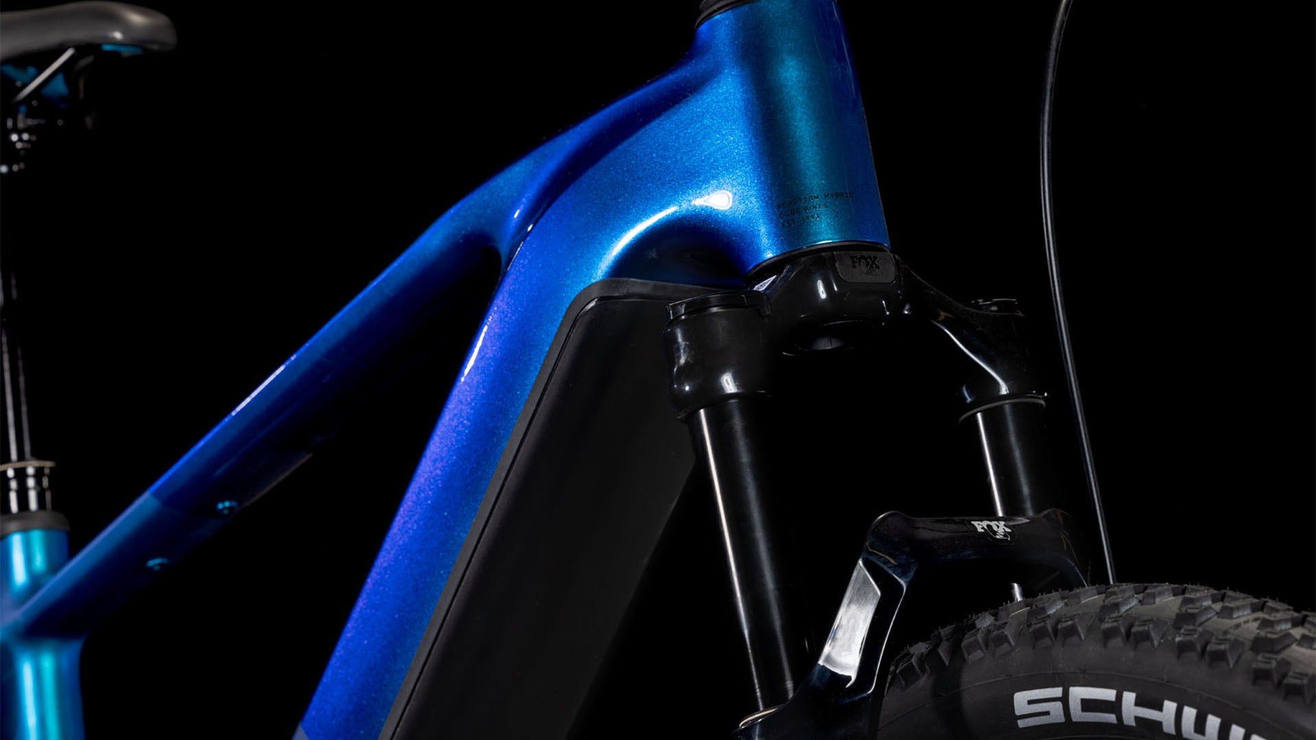 Nahaufnahme eines CUBE Reaction Hybrid SLX 800 nebula'n'blue 2025 Rahmens und einer Federgabel vor schwarzem Hintergrund, die einen Teil des Reifens mit der Marke Schwalbe zeigt.