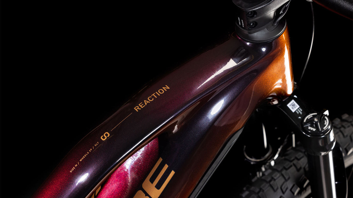 Nahaufnahme des CUBE Reaction Hybrid SLT 800 solareclipse'n'bronze Trapeze 2025 Rahmens mit glänzendem rot-bronzenem Finish, "REACTION" auf dem Oberrohr, sowie Bosch Motor und Sram XO Eagle Getriebe.