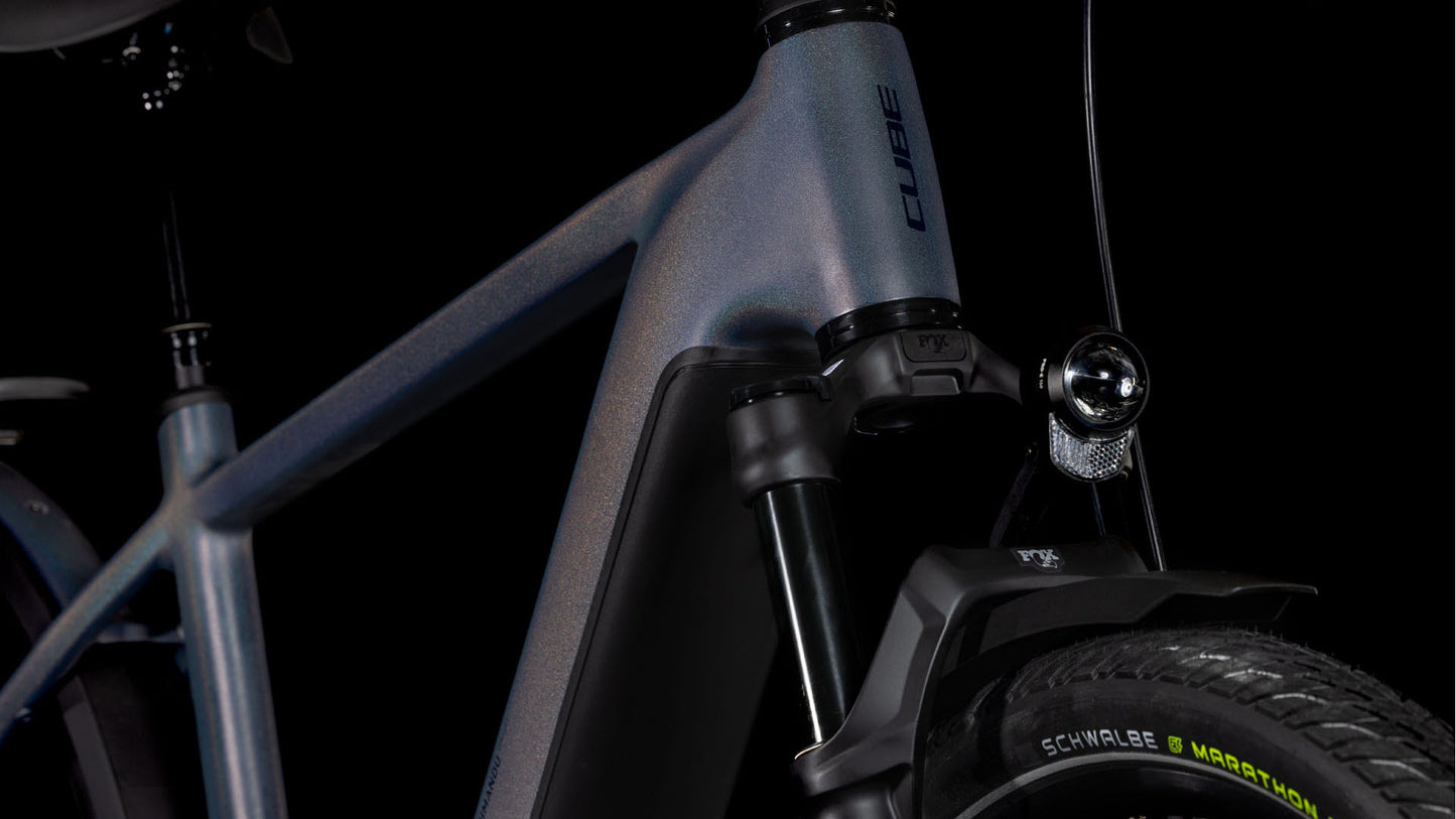 Die Nahaufnahme des Vorderrahmens des CUBE Kathmandu Hybrid Comfort SLX 800 zeigt das CUBE-Logo, die Vorderradaufhängung, den Scheinwerfer, die Schwalbe-Reifen und den leistungsstarken Bosch CX-Motor - alles vor einem schwarzen Hintergrund.
