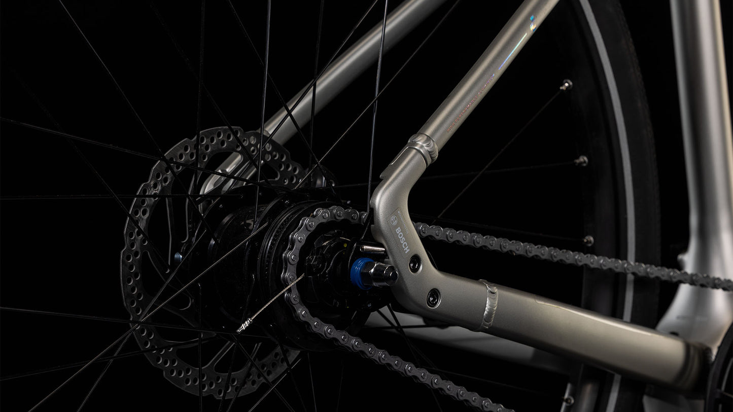Nahaufnahme des CUBE Editor Hybrid SLX 400X sleekgrey'n'spectral 2025 Hinterrads mit Schaltung, Kette, Scheibenbremsscheibe und Rahmen mit Shimano 8-Gang-Nabe vor einem dunklen Hintergrund.