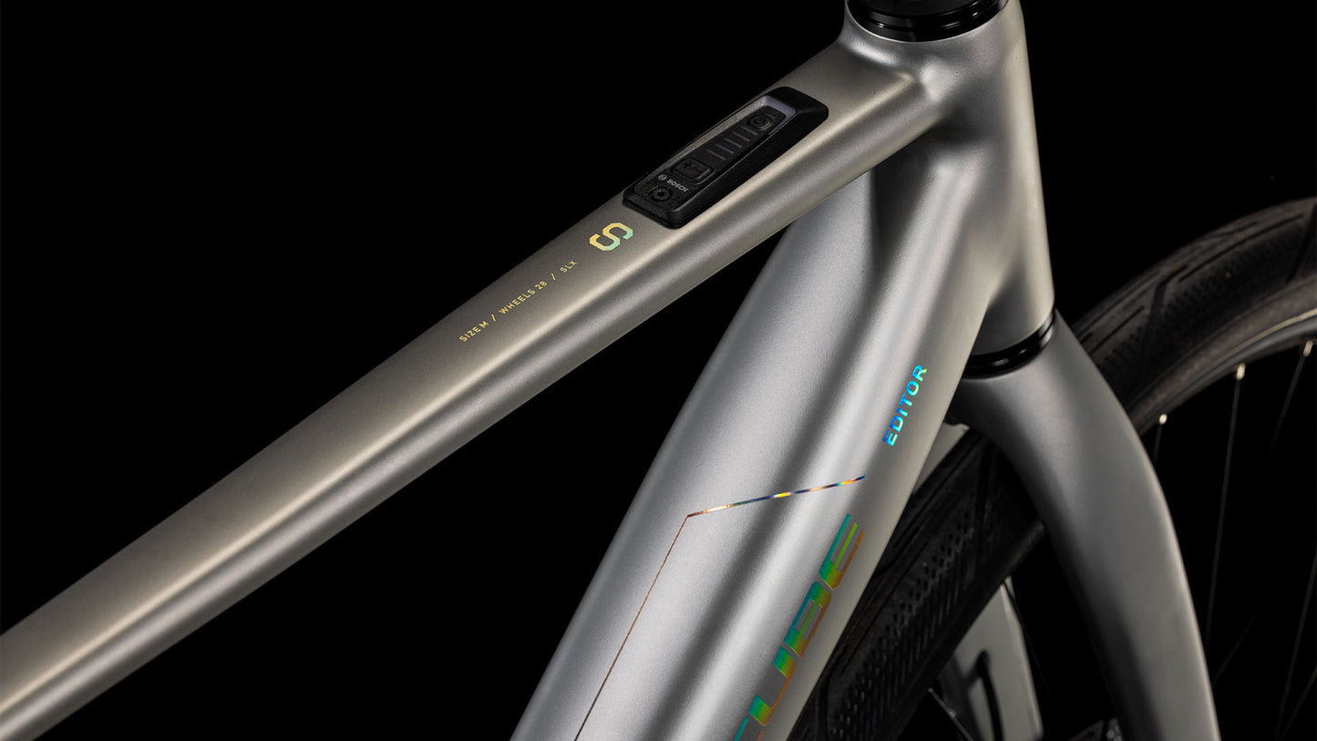 Nahaufnahme des CUBE Editor Hybrid SLX 400X sleekgrey'n'spectral 2025 Rahmens, mit minimalistischem Design, klaren Linien, Branding und einem Bedienfeld am Oberrohr, das vom Bosch SX E-Motor angetrieben wird. Die Shimano 8-Gang-Nabenschaltung ermöglicht reibungslose Schaltvorgänge.