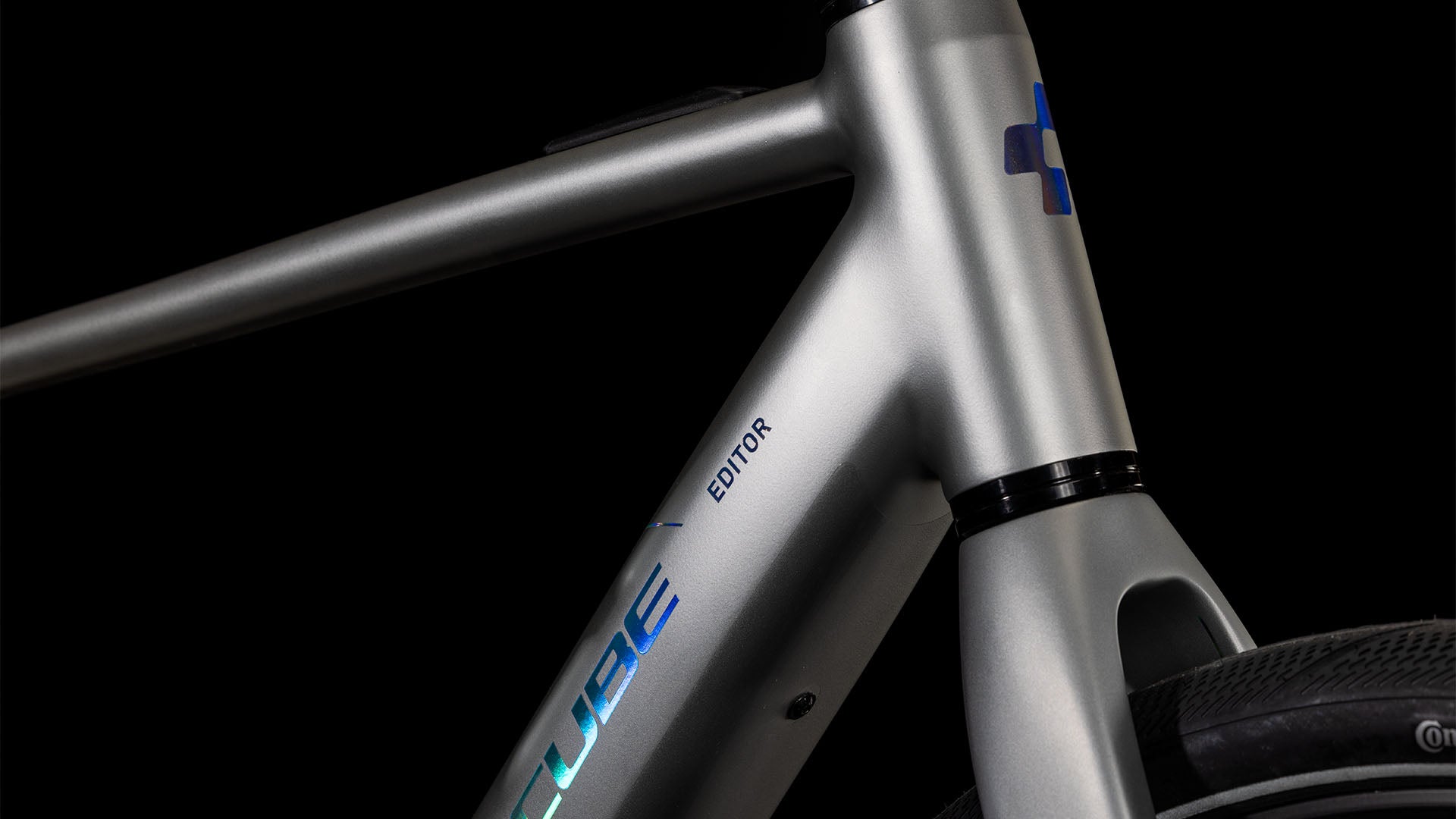 Nahaufnahme des CUBE Editor Hybrid SLX 400X sleekgrey'n'spectral 2025 mit blauem CUBE-Schriftzug, modernem silbernen Rahmen, Shimano 8-Gang-Nabenschaltung und einem Teil des Vorderrads vor schwarzem Hintergrund.