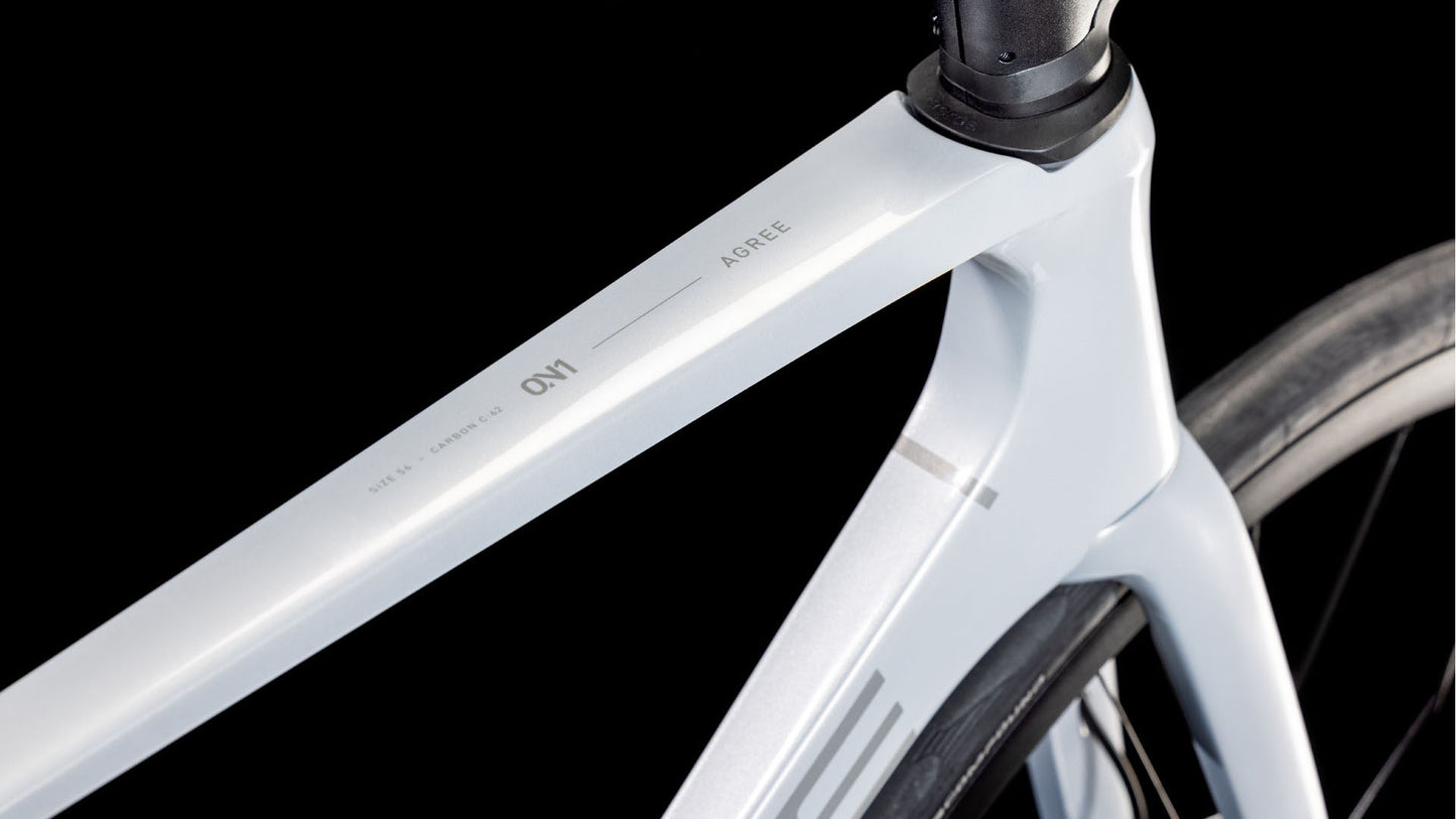 Nahaufnahme des CUBE Agree C:62 ONE foggrey'n'grey 2025, die den schlanken Rahmen und das minimale Design am Übergang zwischen Sitz- und Oberrohr vor einem schwarzen Hintergrund hervorhebt.
