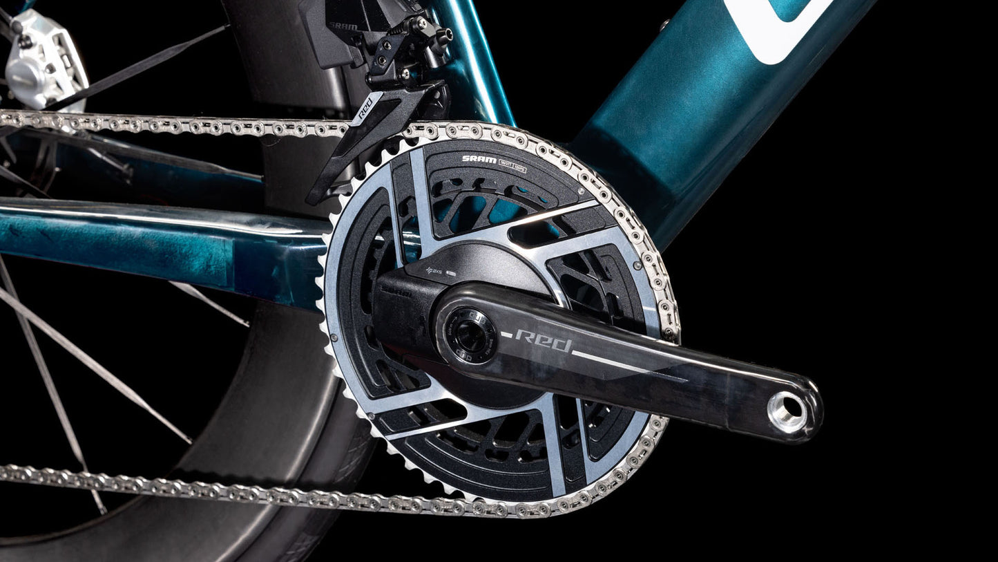 Nahaufnahme der CUBE Litening AERO C:68X SLX chromblue'n'liquidblue 2025 Kurbelgarnitur und Kettenblatt mit silberner Kette, die das aerodynamische Design und die Einhaltung der UCI-Richtlinien vor einem schwarzen Hintergrund hervorheben.