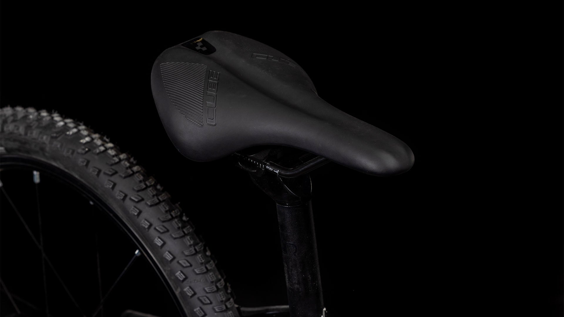 Nahaufnahme des CUBE Numove 180 black'n'orange 2025 Sattel, Sattelstütze und Hinterrad mit genoppten Schwalbe Reifen - die ideale Wahl für jede All-Terrain-Bike Fahrt.