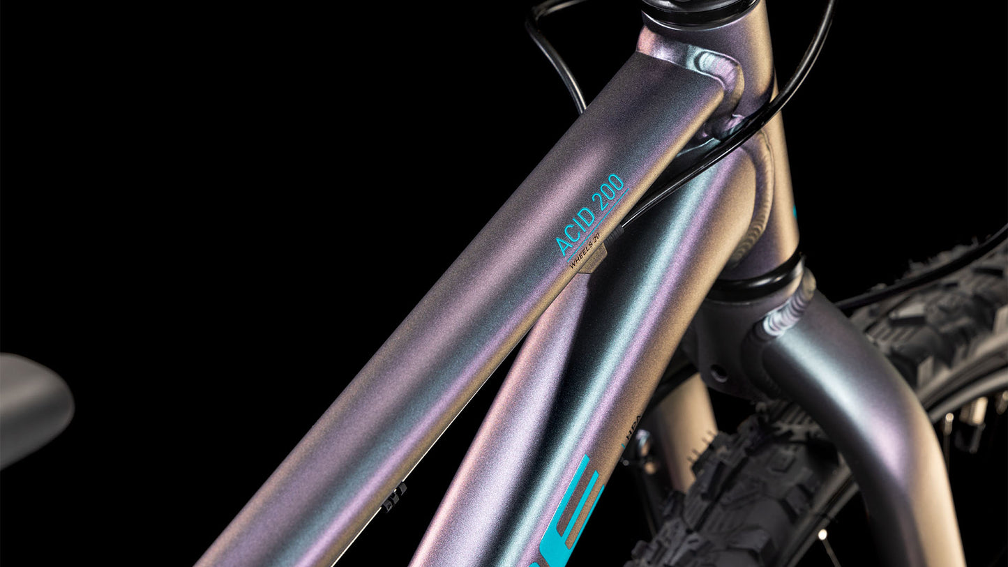 Nahaufnahme des CUBE Acid 200 Disc galactic´n´cyan 2025-Rahmens mit Metallic-Finish, Shimano 7-Gang-Getriebe und sichtbarem Vorderreifen und Gabel vor schwarzem Hintergrund.