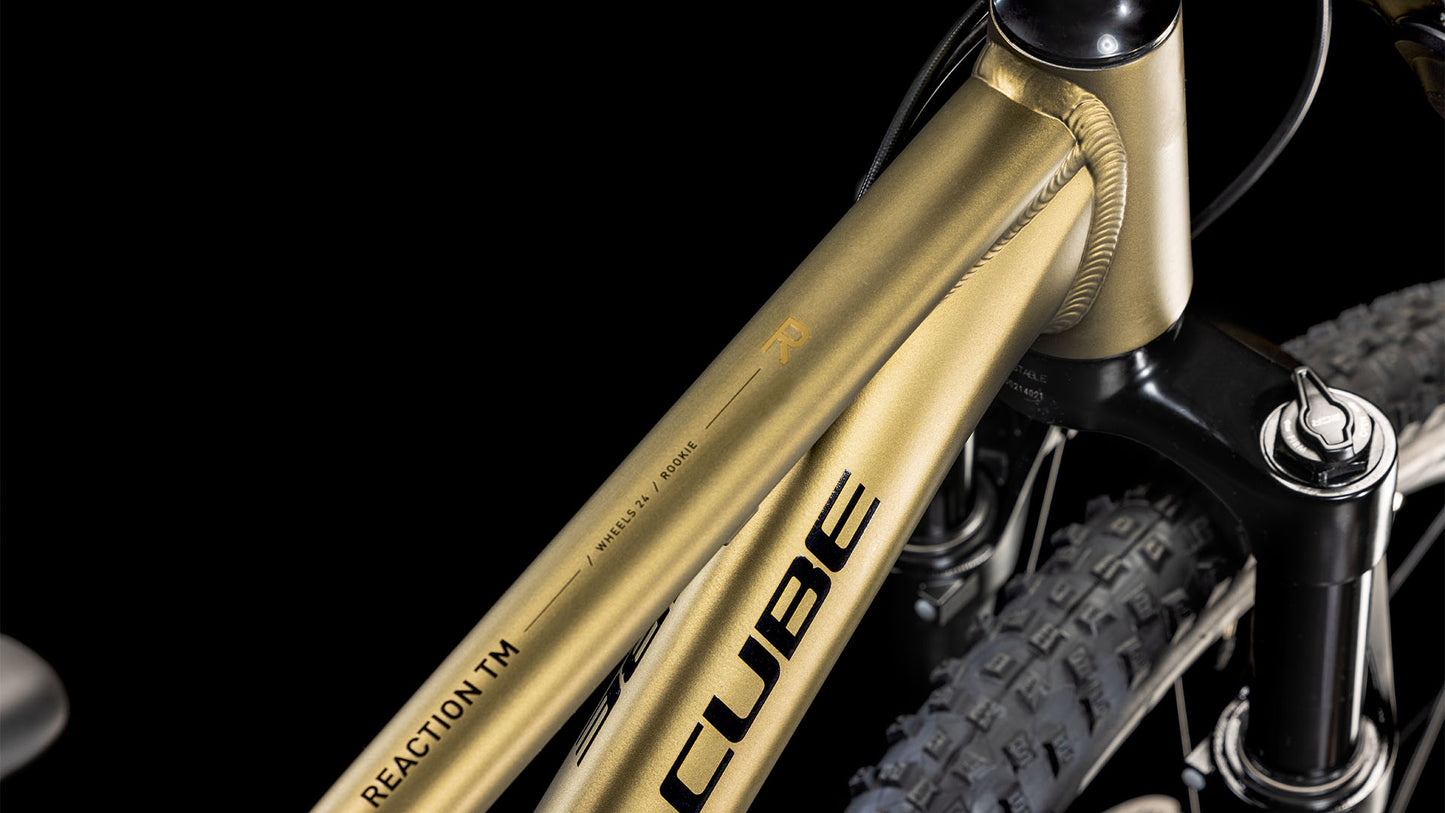 Nahaufnahme des CUBE Reaction 240 TM Goldenlime'n'Black 2025 Rahmens mit REACTION TM Schriftzug, Federgabel, Noppenreifen und Magura MT Trail Sport Bremsen vor schwarzem Hintergrund.