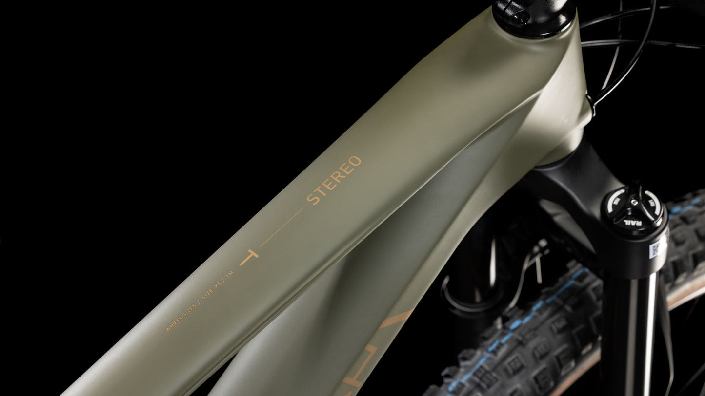 Nahaufnahme des CUBE Stereo ONE44 HPC Rookie dustyolive'n'gold 2025 Carbonrahmens mit STEREO auf dem Oberrohr, Federgabel und Schwalbe Nobby Nic Reifen vor schwarzem Hintergrund.