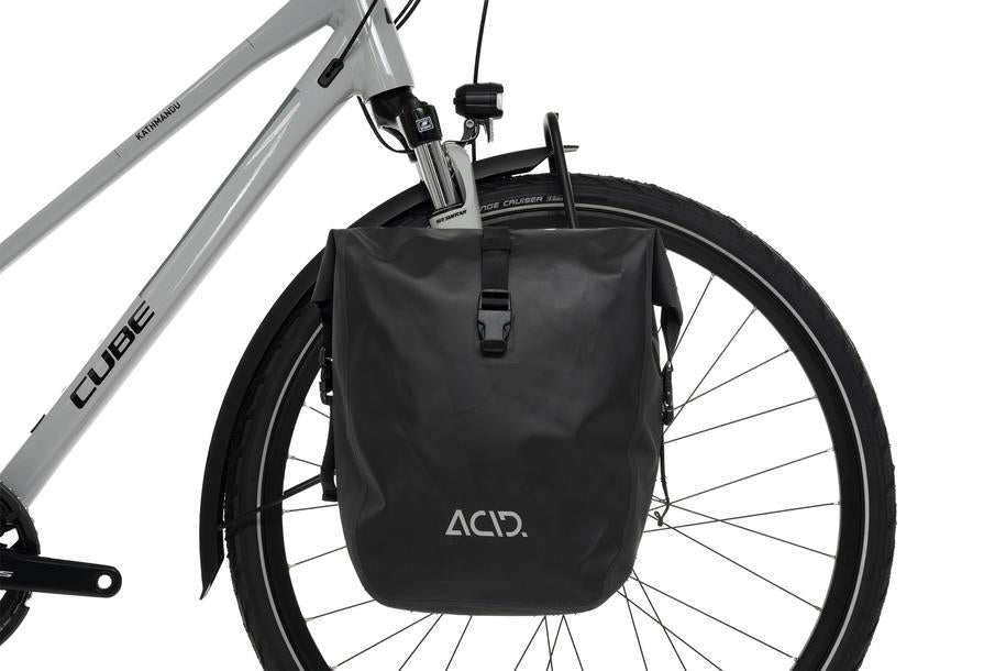 Eine Nahaufnahme des Hinterrads eines Fahrrads mit dem schwarzen ACID Gepäckträger LOWRIDER Suspension MTB und einer passenden wasserdichten Gepäckträgertasche, beides von ACID, auf einem hellgrauen CUBE Rahmen, wie man ihn in einem CUBE Store in Göttingen oder Hildesheim erwarten würde.