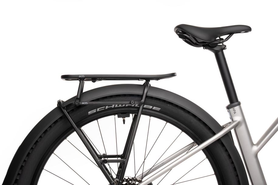 Nahaufnahme des ACID Gepäckträgeraufsatzes SIC 2.0 TOP RAIL von ACID, montiert auf einem Metallrahmen eines Fahrrads mit schwarzem Sattel, Gepäckträger, Federklappe, dickem Schwalbe-Reifen und schwarzem Schutzblech vor einem weißen Hintergrund.