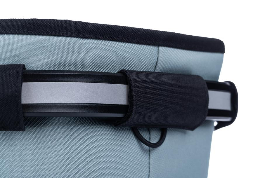 Nahaufnahme des oberen Rands des ACID Gepäckträgerkorbs CITY 20 RILink grau mit schwarzem Rand, schwarzem Band und grauem Metall- oder Kunststoffgriff. Der Hintergrund ist weiß.