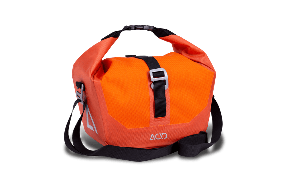 Die ACID Fahrradtasche TRAVLR FRONT 6 FILINK ist eine leuchtend orangefarbene Reisetasche mit schwarzem Schulterriemen, schwarzem Schnallenverschluss, silberner Akzentschnalle und ACID-Logo auf der unteren Vorderseite. Marke: ACID.