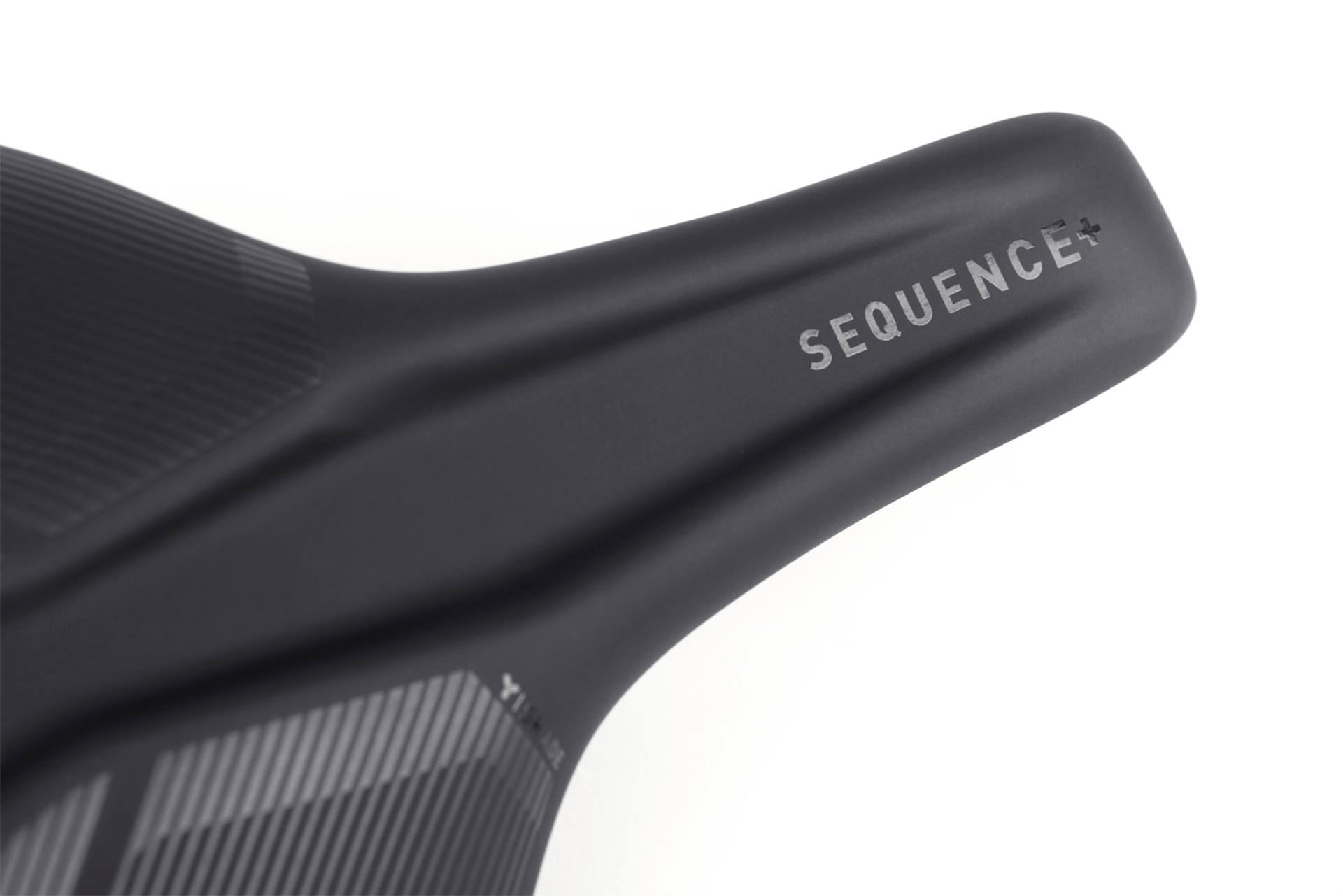 Nahaufnahme des Natural Fit Sattel Sequence+ Regular von Natural Fit, ein schwarzer Sattel mit SEQUENCE+ in weiß, mit Deep-Shell Sattelschale und einer strukturierten Oberfläche für verbesserten Komfort und modernen Stil.