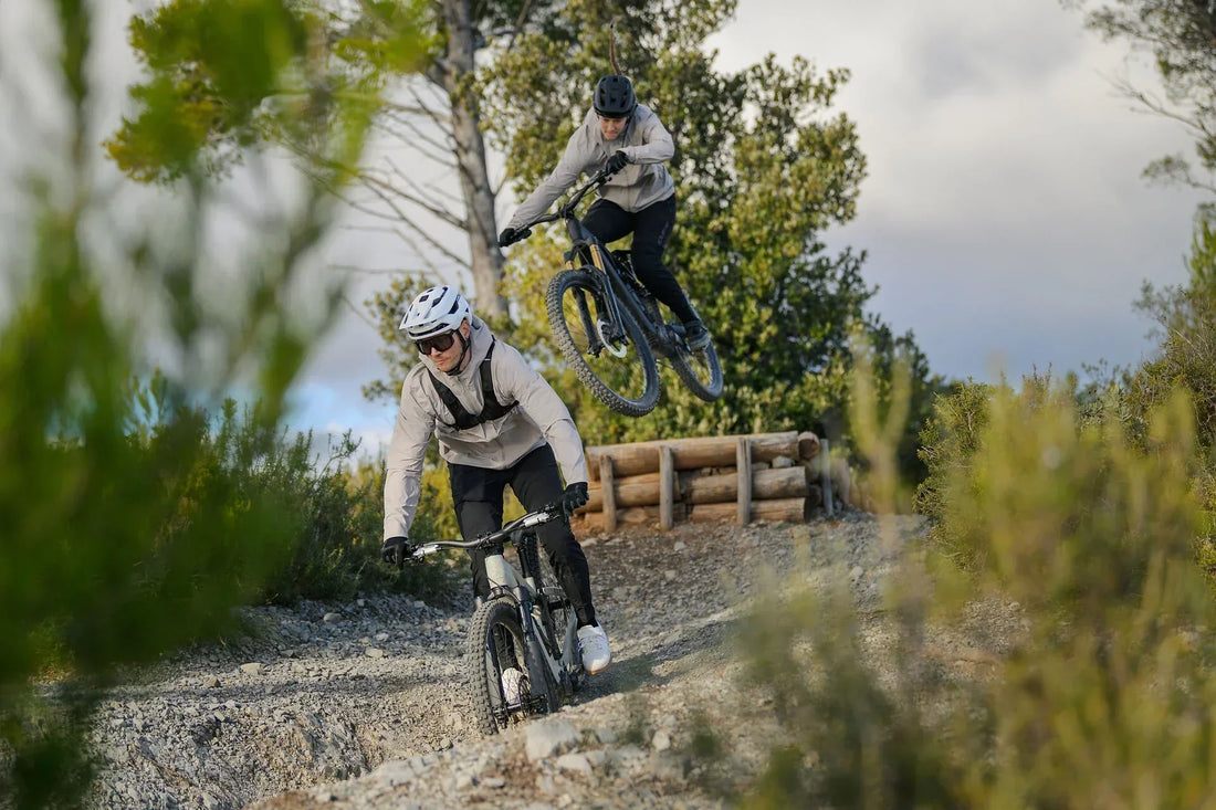 Zwei Mountainbiker fahren auf CUBE AMS Hybrid E-MTBs über einen Trail in der Natur