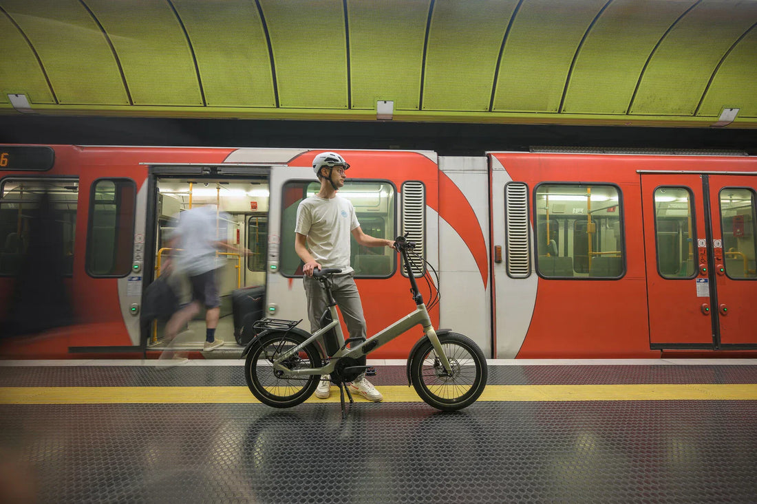 Person mit einem CUBE Fold Falt-E-Bike auf einem U-Bahnsteig vor einem roten Zug