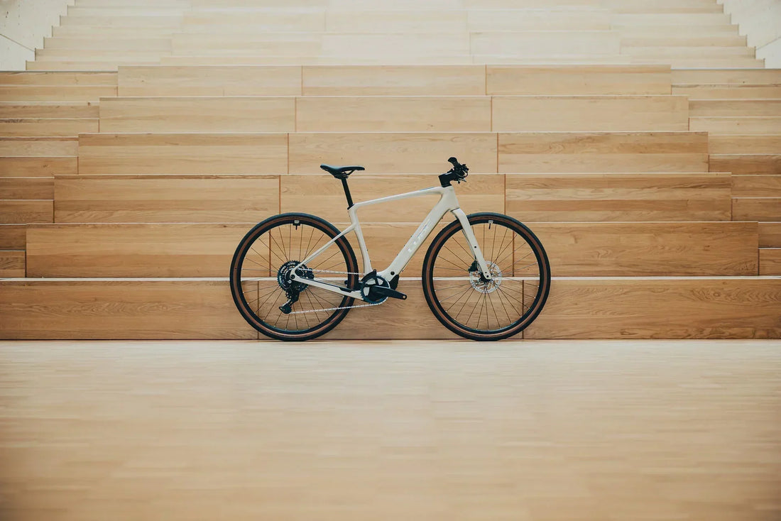 Weißes CUBE Nuroad Hybrid Gravel-E-Bike mit Dropbar-Lenker vor einer Holzwand