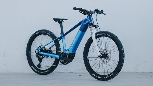 Blaues CUBE Kinder-E-MTB Hardtail vor einer hellen Wand