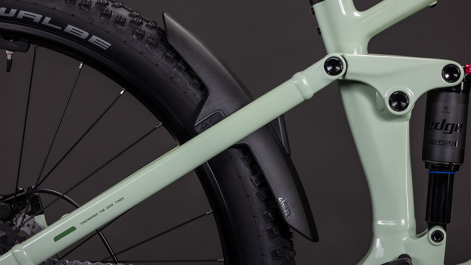 Nahaufnahme des CUBE Stereo Hybrid ONE22 Pro 800 stonegrey'n'black 2026 E-Mountainbike-Rahmens. Hervorzuheben sind die Hinterradfederung, die Schwalbe-Reifen, das schwarze Schutzblech und sichtbare CUBE Kinematik-Details vor einem dunklen, unscharfen Hintergrund.